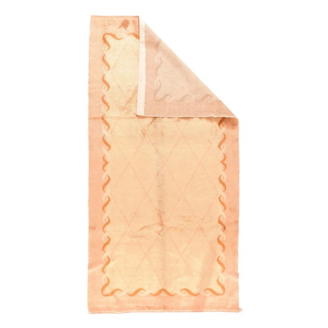 This vintage European long rug shows an ecru beige field, with s subtle hairline lozenge lattice, edged by a guilloche...