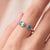 A bold, contemporary open-cuff ring featuring two brilliant blue topaz stones — an oval-cut stone paired with a round-cut...