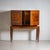 Two-door wooden bar cabinet on tall tapered legs with recessed panels, decorated with antique amphora motifs and meander...