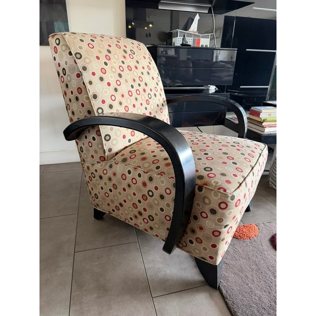 This stylish upholstered armchair features a bold, graphic circular motif iin warm neutral tones accented with red and...