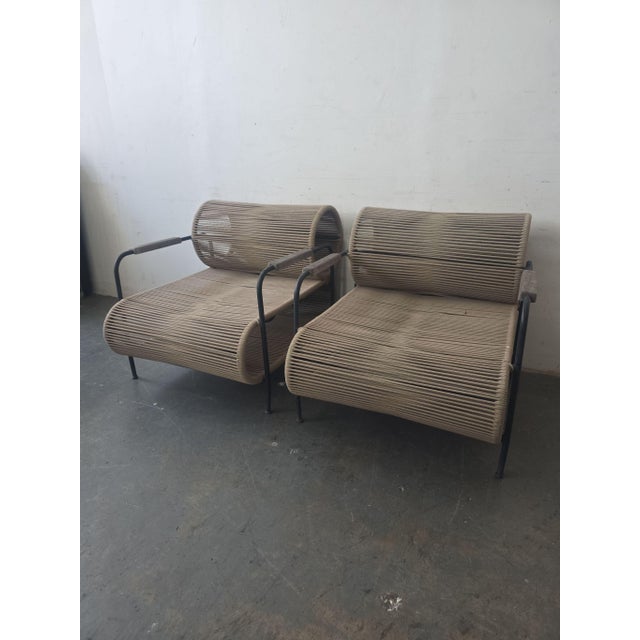 This set includes two stylish lounge chairs featuring a sturdy black metal frame and a unique rope design for the seat and...