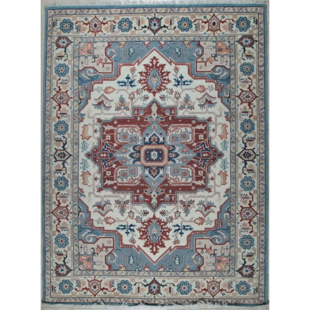 A hand-knotted wool rug, made in India and measuring 9' x 12'. A centre medallion anchoring the field, framed by a...