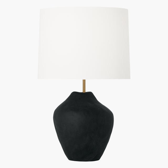 Handcrafted in ceramic, the Cadley one-light table lamp by Hable features a uniquely shaped base in a black or white...