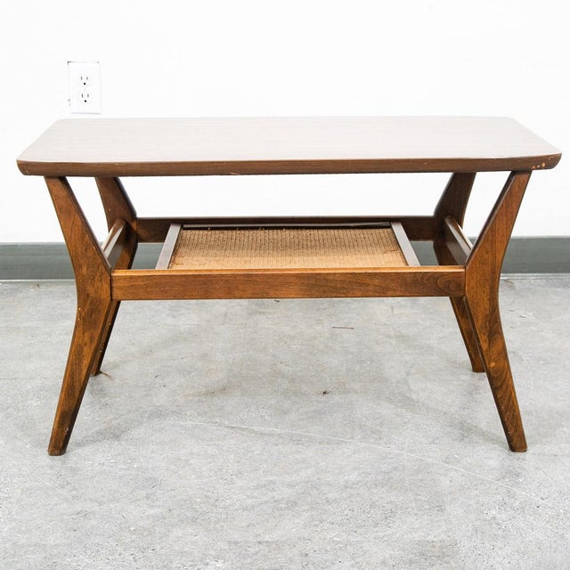 American designed coffee table with laminate top surface and cane shelf below. Sculptural wood legs throughout. Unsigned.