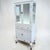 A vintage metal painted medical cabinet. An unusual form having 2 doors above 3 drawers above 2 more doors again for more...