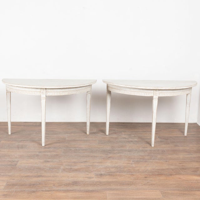 Pair, Gustavian demi-lune side tables or consoles with gently tapered legs and decorative egg and dart carving along...