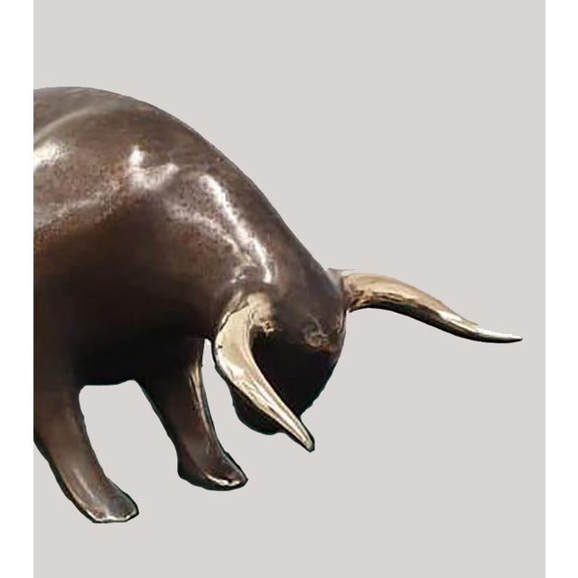 A contemporary animal bronze of a bull head-down mid-charge, tail flicked high and horns lowered to strike — the whole...