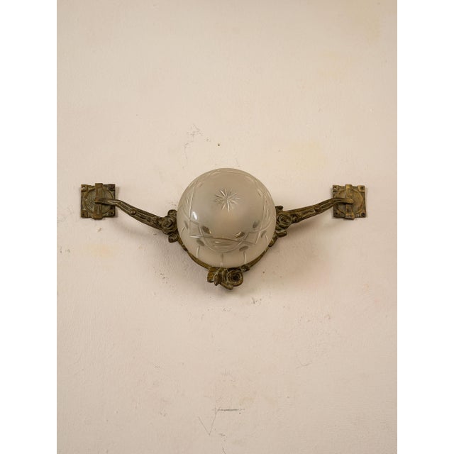Art Nouveau wall lamp, Italy, early 1900s. The wall lamp is made of cast brass and is embellished with a frosted glass...