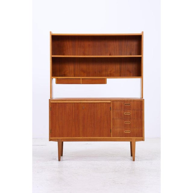 Vintage shelving unit with a chest of drawers and a teak shelf above. The lower section features two doors and four large...