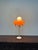 A striking vintage Space Age table lamp from the 1970s, featuring four spherical glass globes in vibrant orange and white....