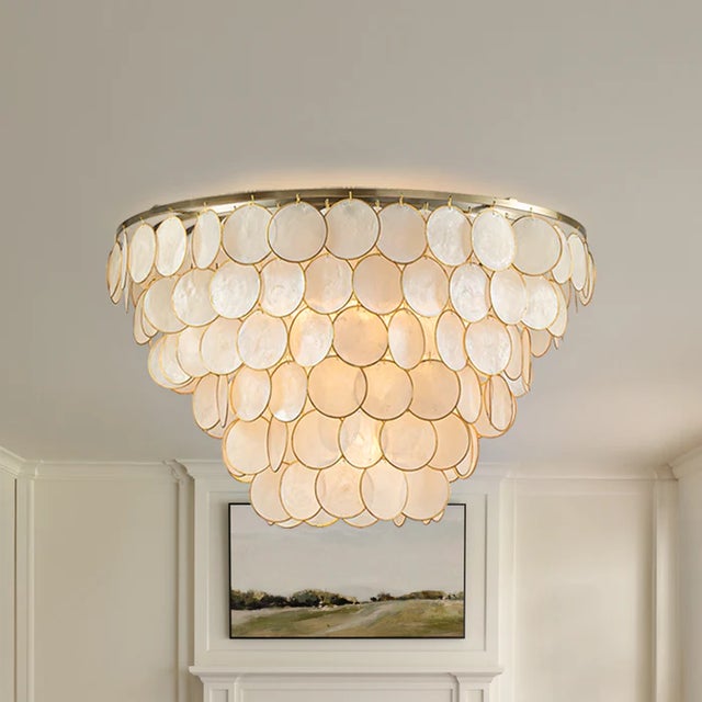 ALOADECOR natural Capiz shell tiered chandelier with a warm aged-brass/bronze tone metal frame. The layered round shell...