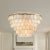 ALOADECOR natural Capiz shell tiered chandelier with a warm aged-brass/bronze tone metal frame. The layered round shell...