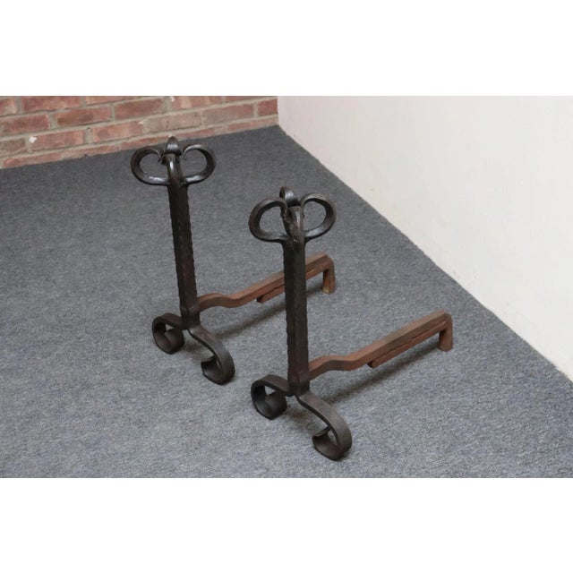 Arts & Crafts-era andirons composed of scroll-clusters atop slender hammered uprights attached to iron billet bars (ca....