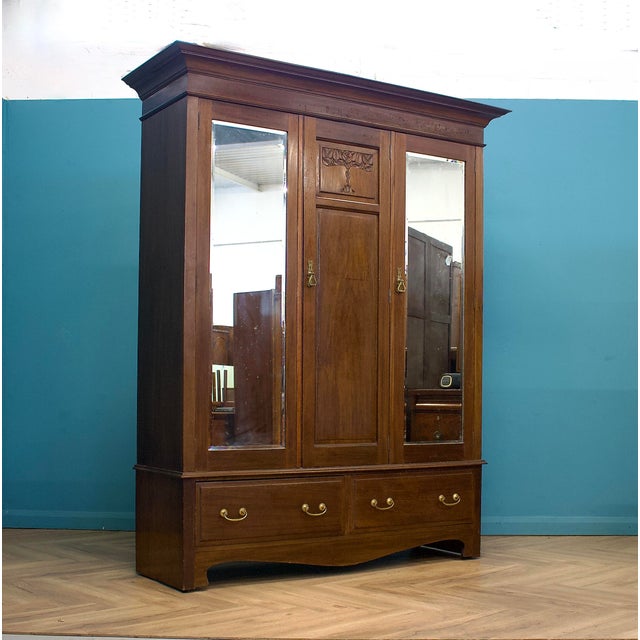 An elegant antique wardrobe crafted from solid oak with rich mahogany veneers, offering quality craftsmanship. It features...