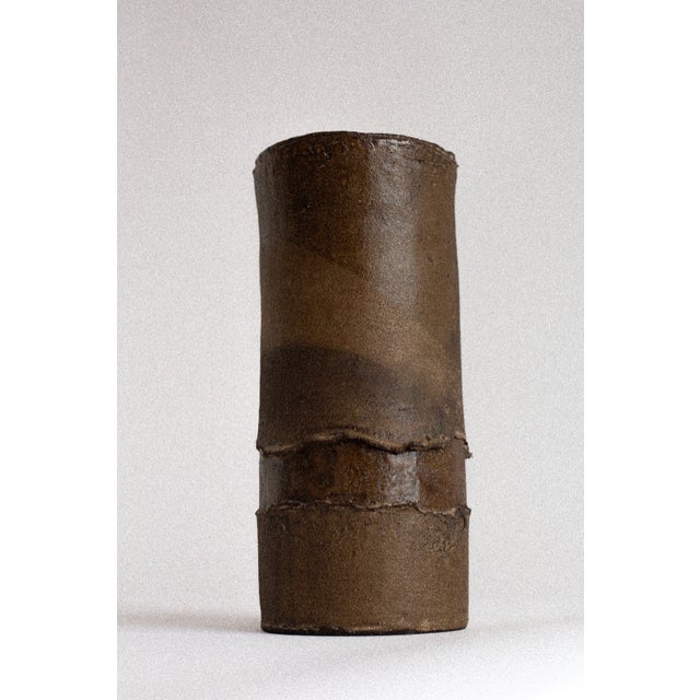 with its softly irregular silhouette and dark, earth-toned surface, this hand-built stoneware vessel carries a quiet sense...