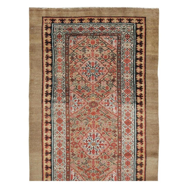 This early 20th-century Persian Serab runner presents a finely organized geometric-floral composition across a warm camel...