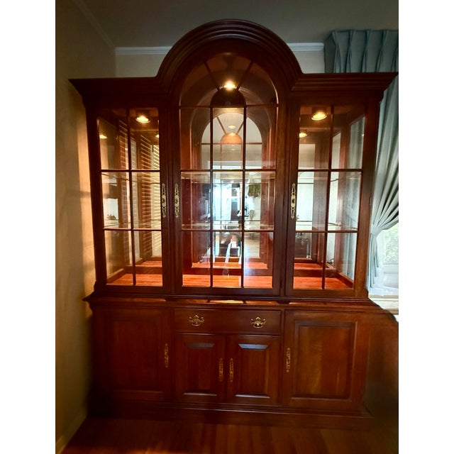 Solid cherry breakfront china cabinet by Pennsylvania House with a lighted arched display cabinet, beveled glass doors,...