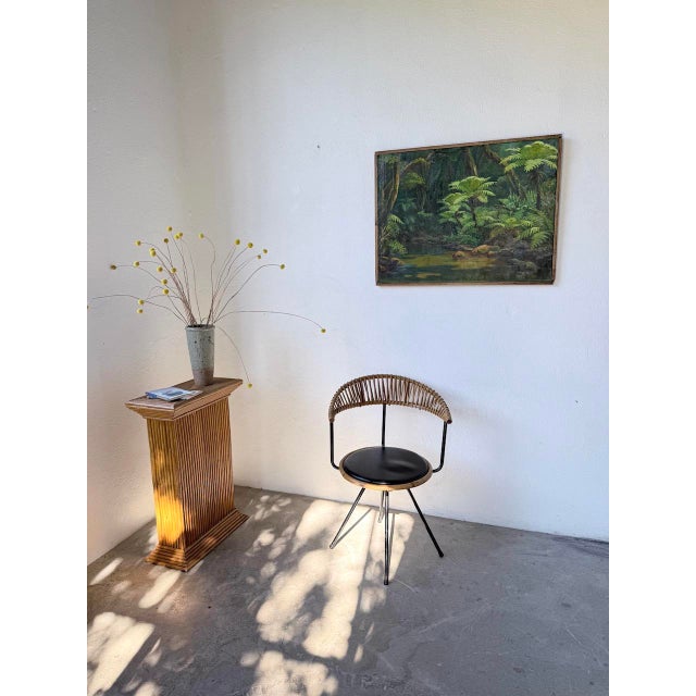 Vintage 1950s rattan chair with a black lacquered metal frame and a rattan and woven wicker seat and back. Designed by the...