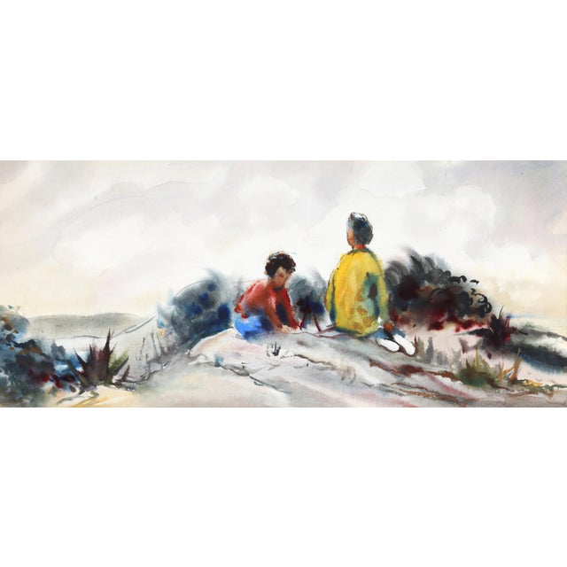 Sitting on a sand dune, two children play together at the beach amongst the beachgrass in this playful, picturesque...