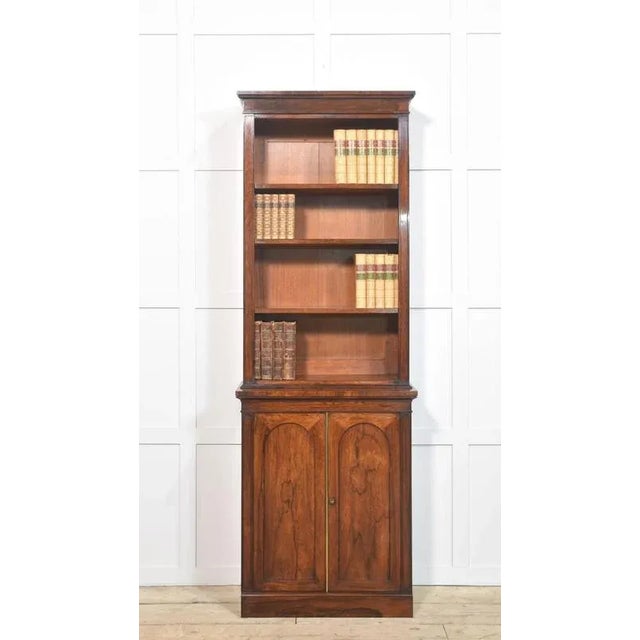 19th-century bookcase, the moulded cornice above the adjustable shelved interior encased by a rosewood frame. To the base...