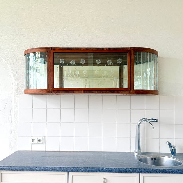 This is an elegant wall-mounted display cabinet that originated in Poland. It was produced in the 1950s and 1960s and was...