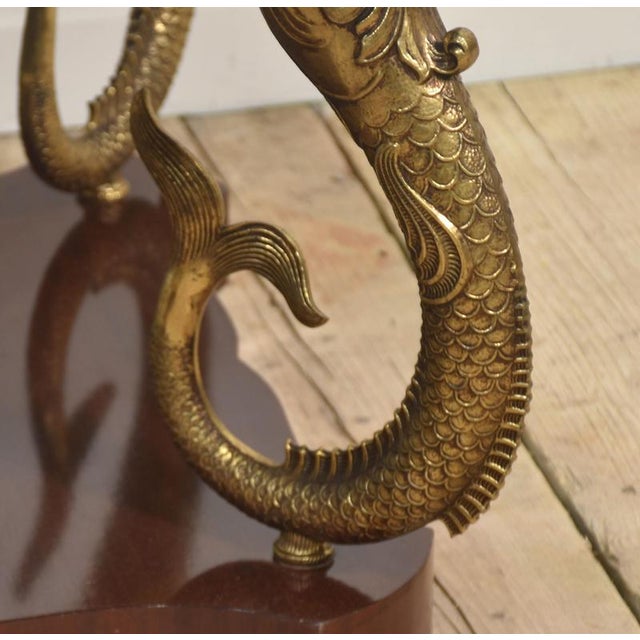 Coffee table having a circular marble top raised on four gilt metal dolphins on a shaped mahogany platform base....