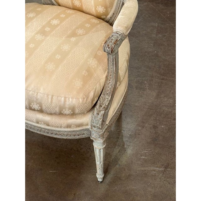 The 18th Century French Louis XVI Carved and Painted Armchair is a beautiful classic piece of furniture. With intricate...