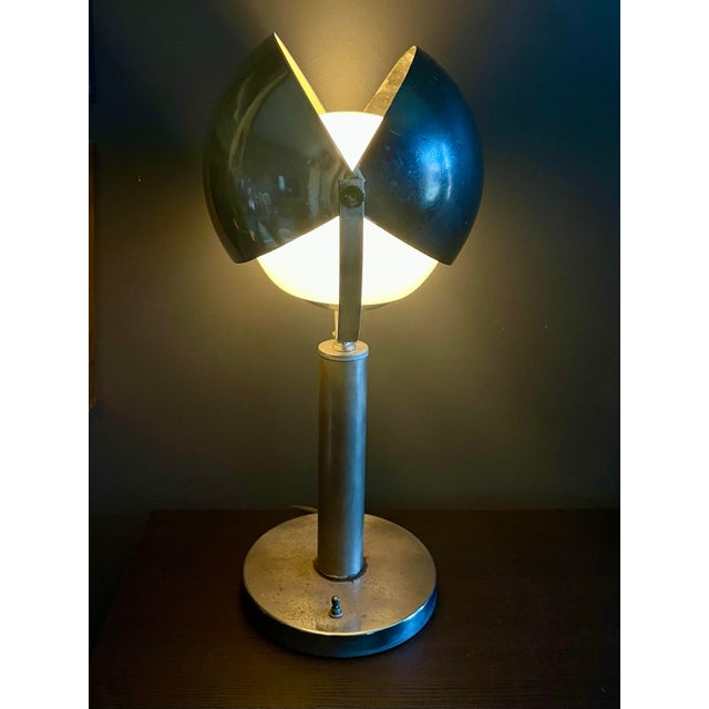 A sculptural mid-century modern table lamp defined by its architectural clarity and adjustable, petal-style shade. Crafted...