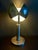 A sculptural mid-century modern table lamp defined by its architectural clarity and adjustable, petal-style shade. Crafted...