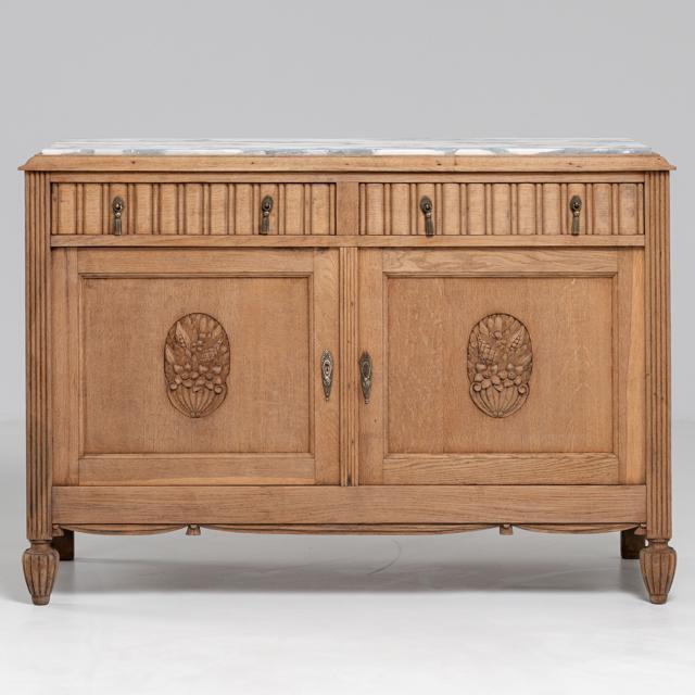 An Art Nouveau oak buffet featuring soft curvature and a marble top. The piece incorporates flowing lines and decorative...
