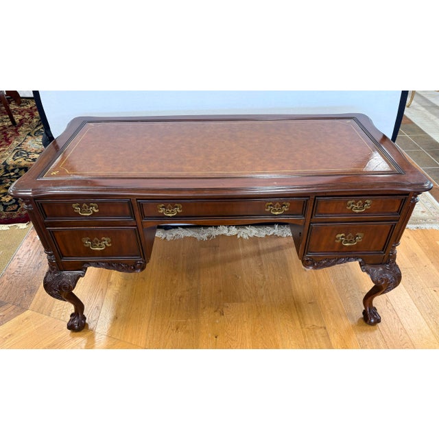 Handsome Sligh mahogany executive desk with a brown tooled leather writing surface, five drawers, and decorative brass...