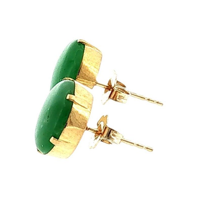 A late 20th-century pair of 11mm green jade stud earrings. The settings are crafted from 20k with 14k gold posts. Total...