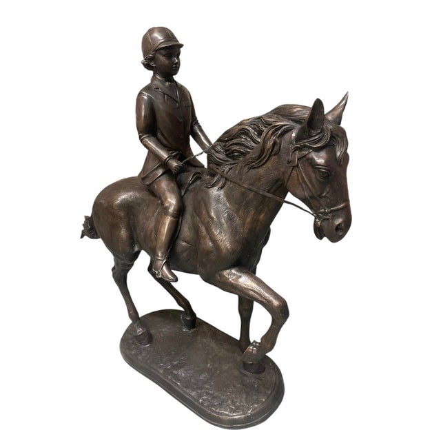 This elegant bronze sculpture captures a moment of poised athleticism, featuring a young rider—likely a boy in hunt or...