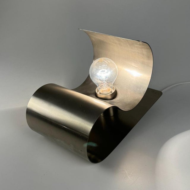 Mid-Century Modern Bent Brushed Steel Wall Lamp, 1970s, in Very Good conditions. Designed 1970 to 1979 Up to 250V...