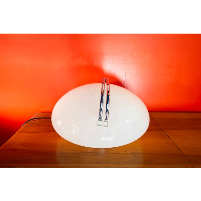 Table lamp with a chromed metal base and an opal glass shade. Interactive mechanism based on a chromed path that can be...