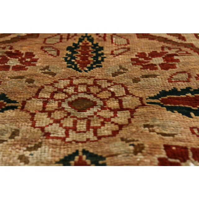 Hand knotted in a lightly distressed, luminous silk body originating from Persia in 1900, this antique Tabriz Persian rug...