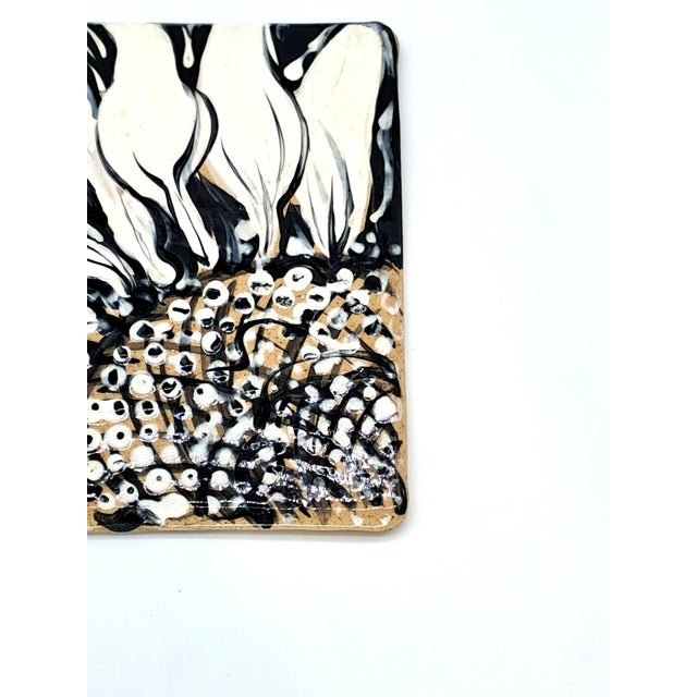 This striking hand-painted trivet features a detailed closeup of a white and black flower. It was made by ceramic artist...