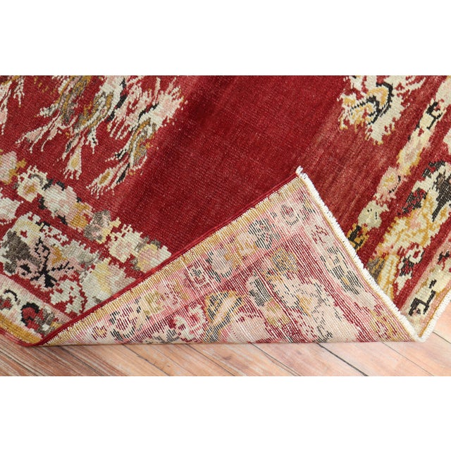 A finely woven Turkish rug executed with pristine jewel-tone colors. A cherry red open field spacious motif. The floral...