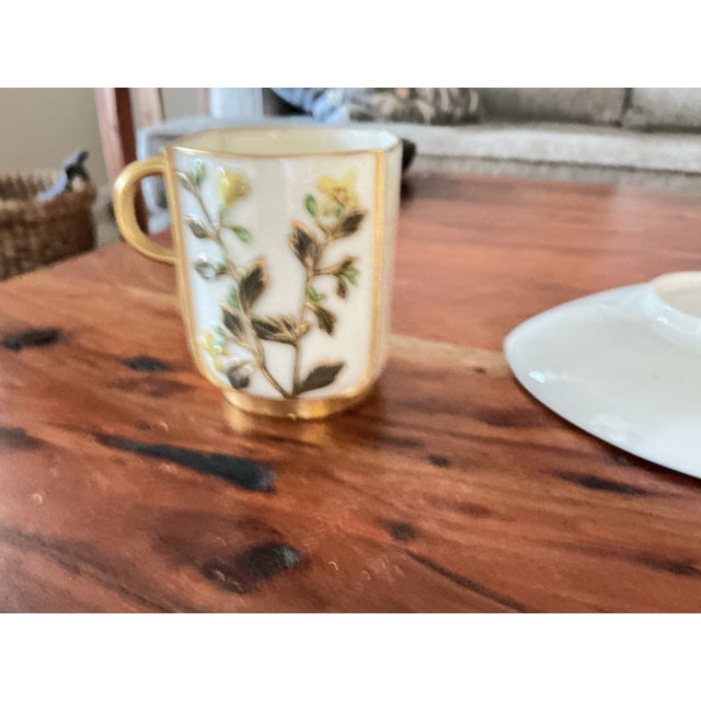 This is a Royal Worcester teacup and saucer featuring intricate, raised flora, colors of yellow and pink flowers. It is...