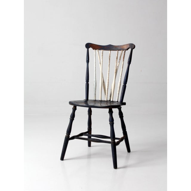 An antique brace-back Windsor chair dating from the late 19th to early 20th century, featuring a dark blue painted frame...