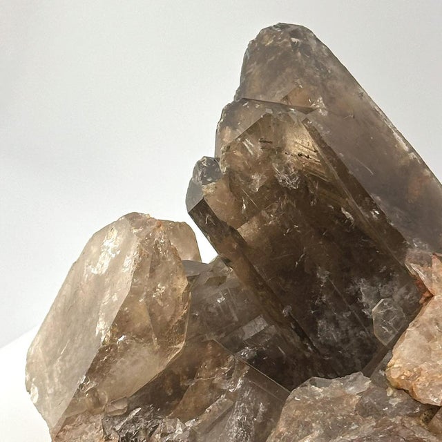 A visually dynamic smoky quartz crystal cluster, showcasing multiple sharply terminated points growing from a natural...
