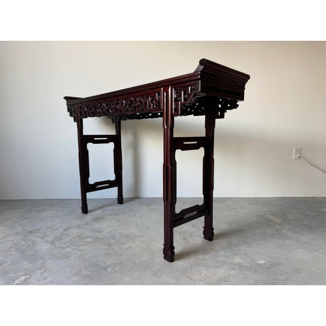 An impressive vintage Chinese altar table crafted from rich rosewood, featuring traditional scroll top ends and an...