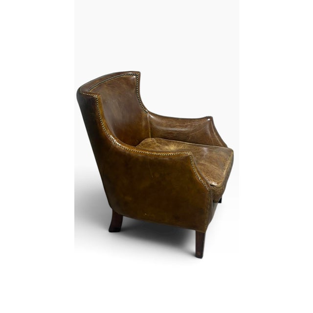 We are pleased to present this wonderfully aged brown leather armchair. There are no cracks or rips on this chair, just...