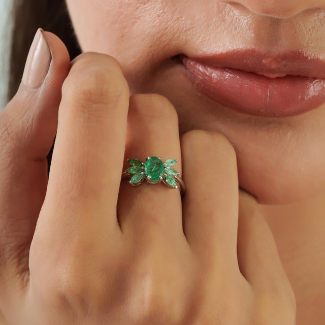 A 1.41 ct certified natural emerald takes center stage in this elegant wing-inspired cluster ring, crafted in 925 sterling...