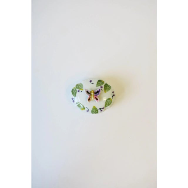 A beautiful white porcelain oval jewelry or trinket box with colorful butterfly, leaves and cherries, circa mid-20th...