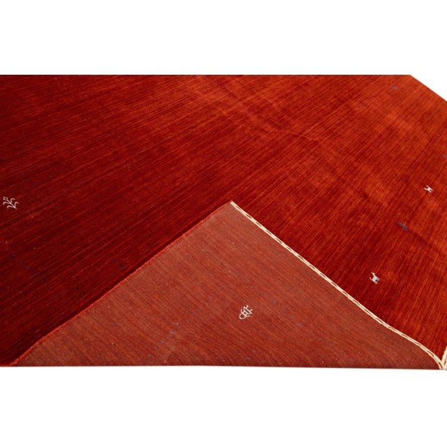 Beautiful modern Gabbeh style hand-Loom wool rug with a red field. This Gabbeh-style rug has blue and white accents in a...