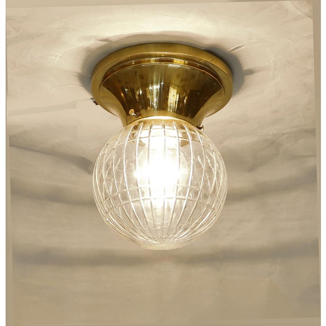 Two Art Nouveau ceiling lamps, circa 1915. Bowl-shaped brass body. Clear glass shades with geometric cut-glass decoration....