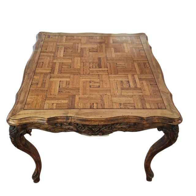 French provincial/Louis XV style table with parquetry top, floral carved apron and legs. Wood appears to be either beech...