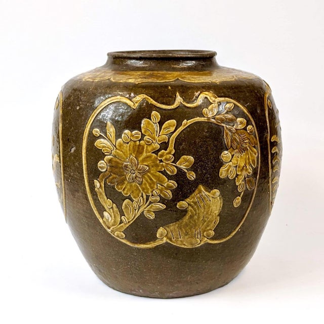 Beautiful brown and yellow ceramic pot that shows 4 intricate reliefs of birds and flowers.