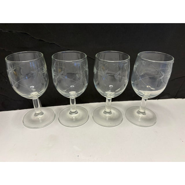 A refined set of four mid-century etched wine glasses showcasing an elegant floral starburst motif with delicate vine...
